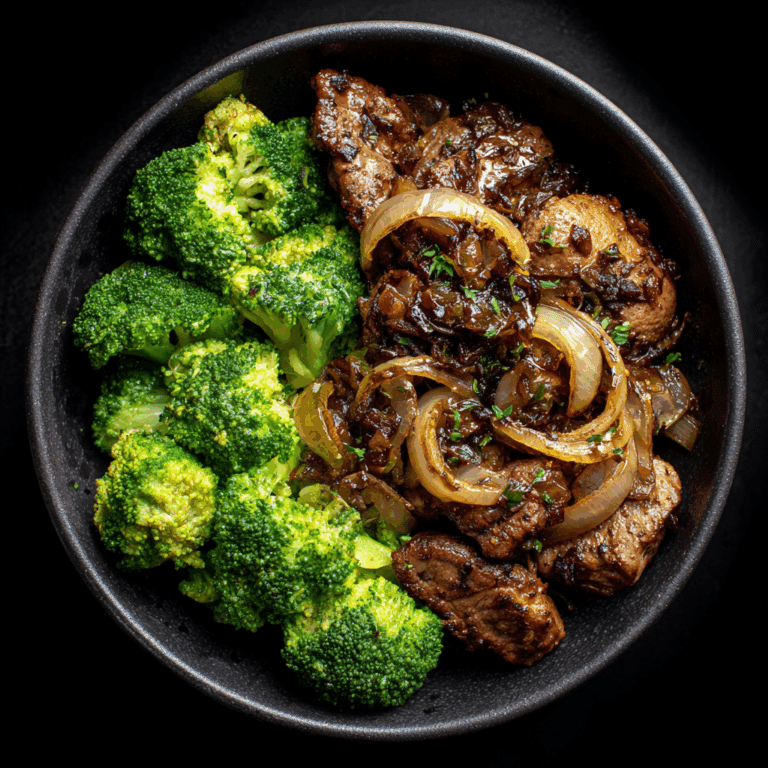 Golden sautéed chicken livers topped with caramelized onions, served on a white plate with a side of green vegetables.
